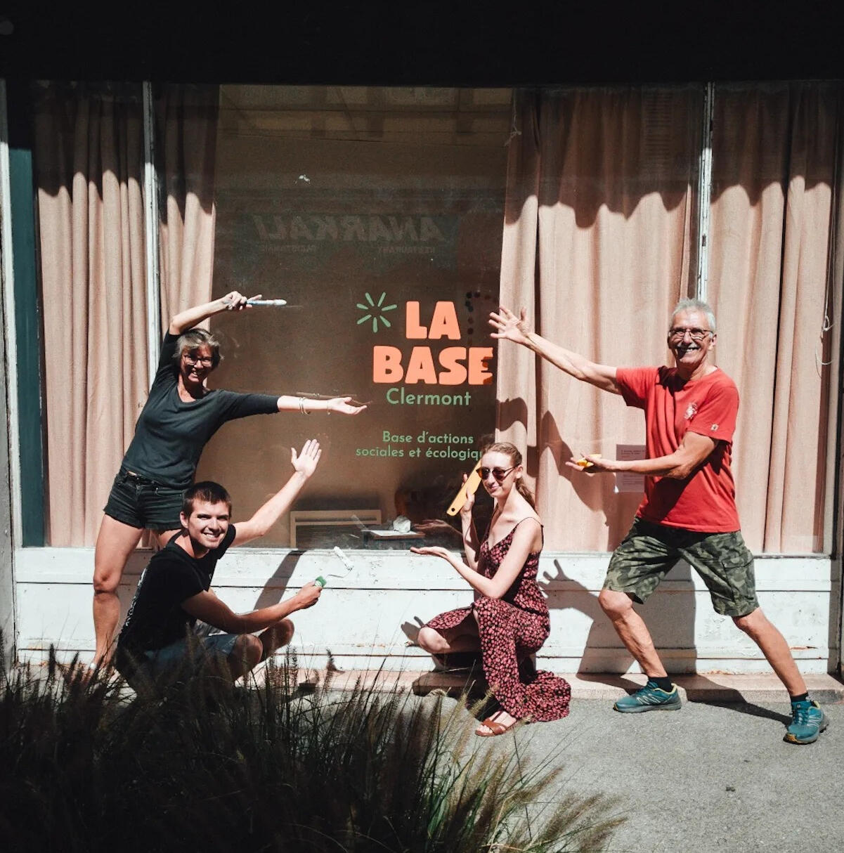 photo des bénévoles devant la vitrine et le logo de la base, tout sourire et qui indiquent le logo avec leurs bras